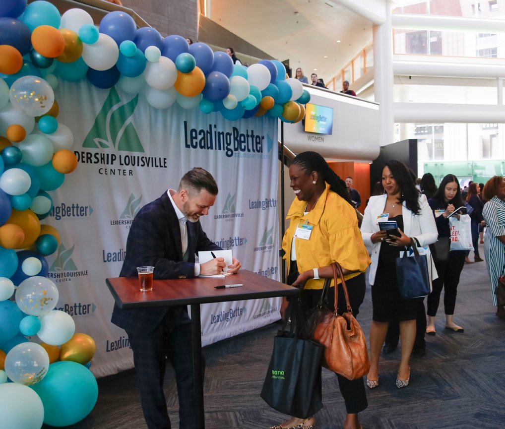 Attendees talking in the Kentucky Center lobby during a book signing at the 2026 LeadingBetter Summit